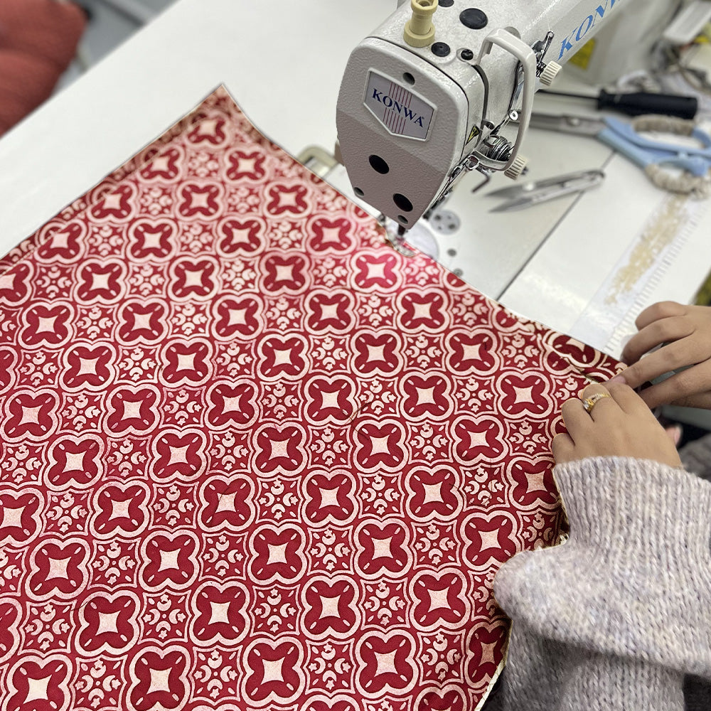 a seamstress is sewing batik fabric in crimson celestial
