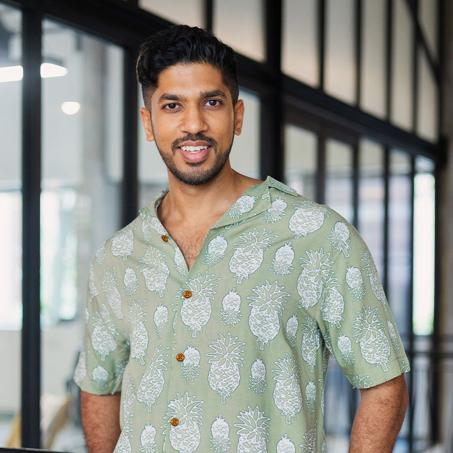 a lifestyle photo of a man wearing a batik shirt in pineapple motif in the color olive from batik boutique