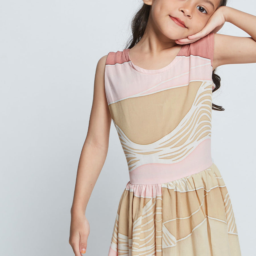 Close-up of girl's sleeveless pink batik dress from Batik Boutique's Raya 2023 collection in Dawn Bukit print as she poses with hand on cheek.