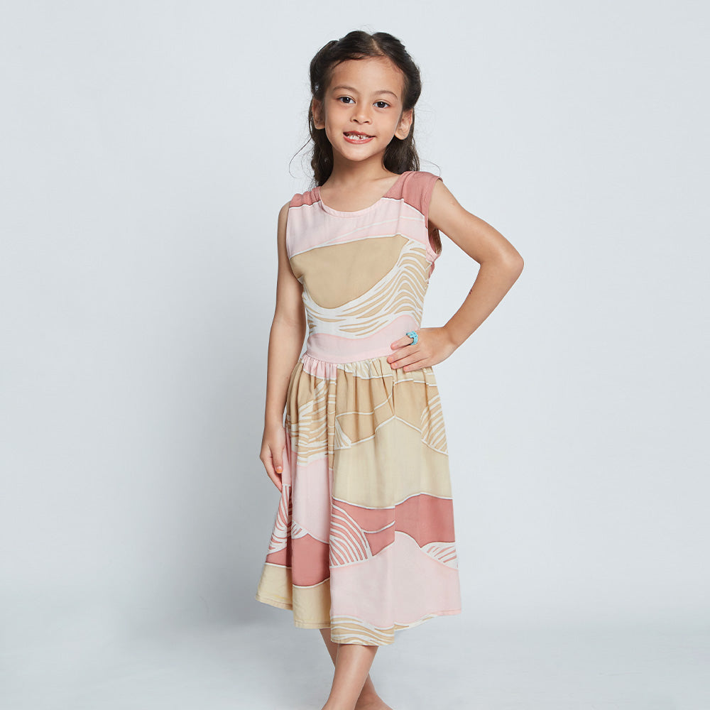 Young girl wearing pink, tan and white batik dress with hand on hip from Batik Boutique's Raya 2023 collection in Dawn Bukit print.