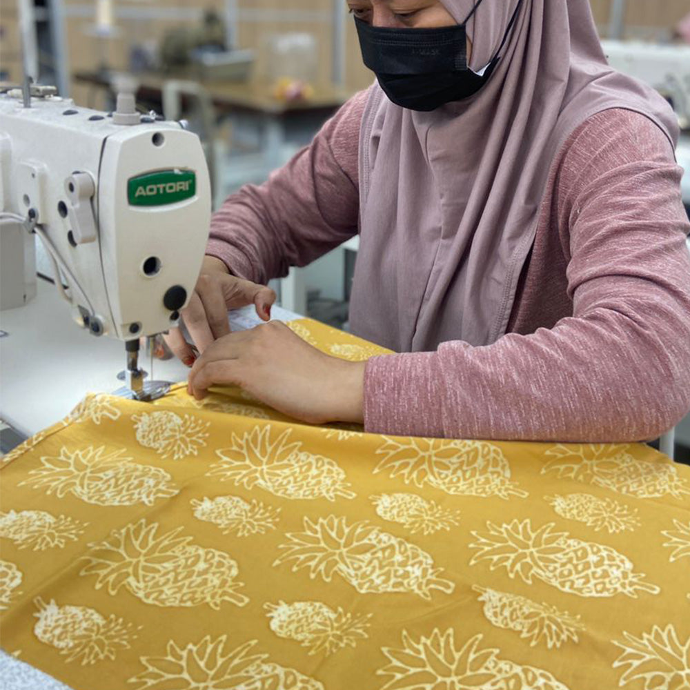 an artisan sewing golden pineapple batik