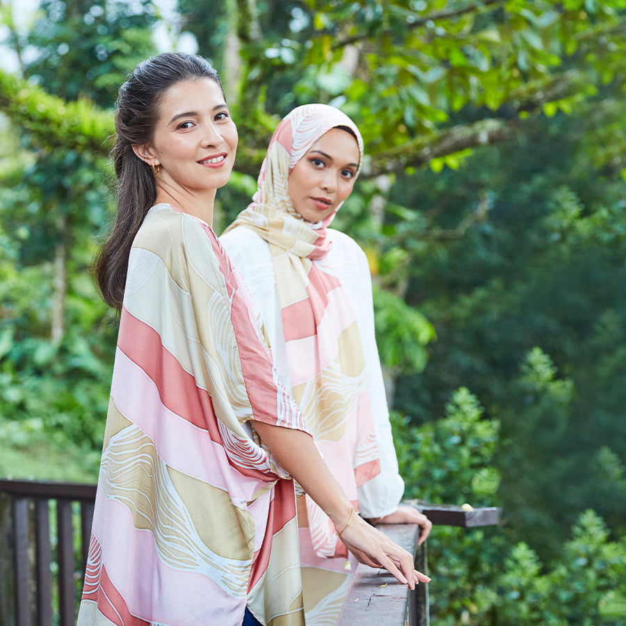 Two women in Dawn Bukit print apparel, posing outdoors against lush green backdrop.