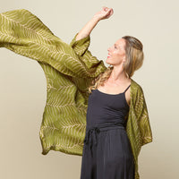 A model is posing with a flowy batik kimono in moss fern pattern