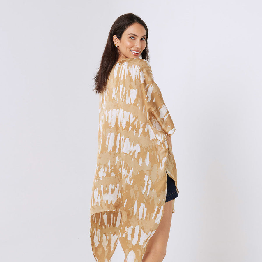 a woman standing in front of white background styling batik long kimono in ultra golden pattern