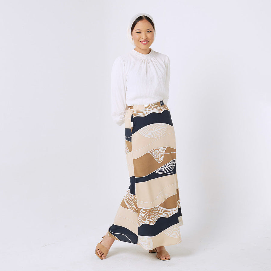  a woman standing in front of white background styling batik long skirt in  black bukit pattern