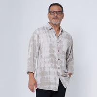 a man posing in front of a white wall while wearing a shibori shirt in mangosteen