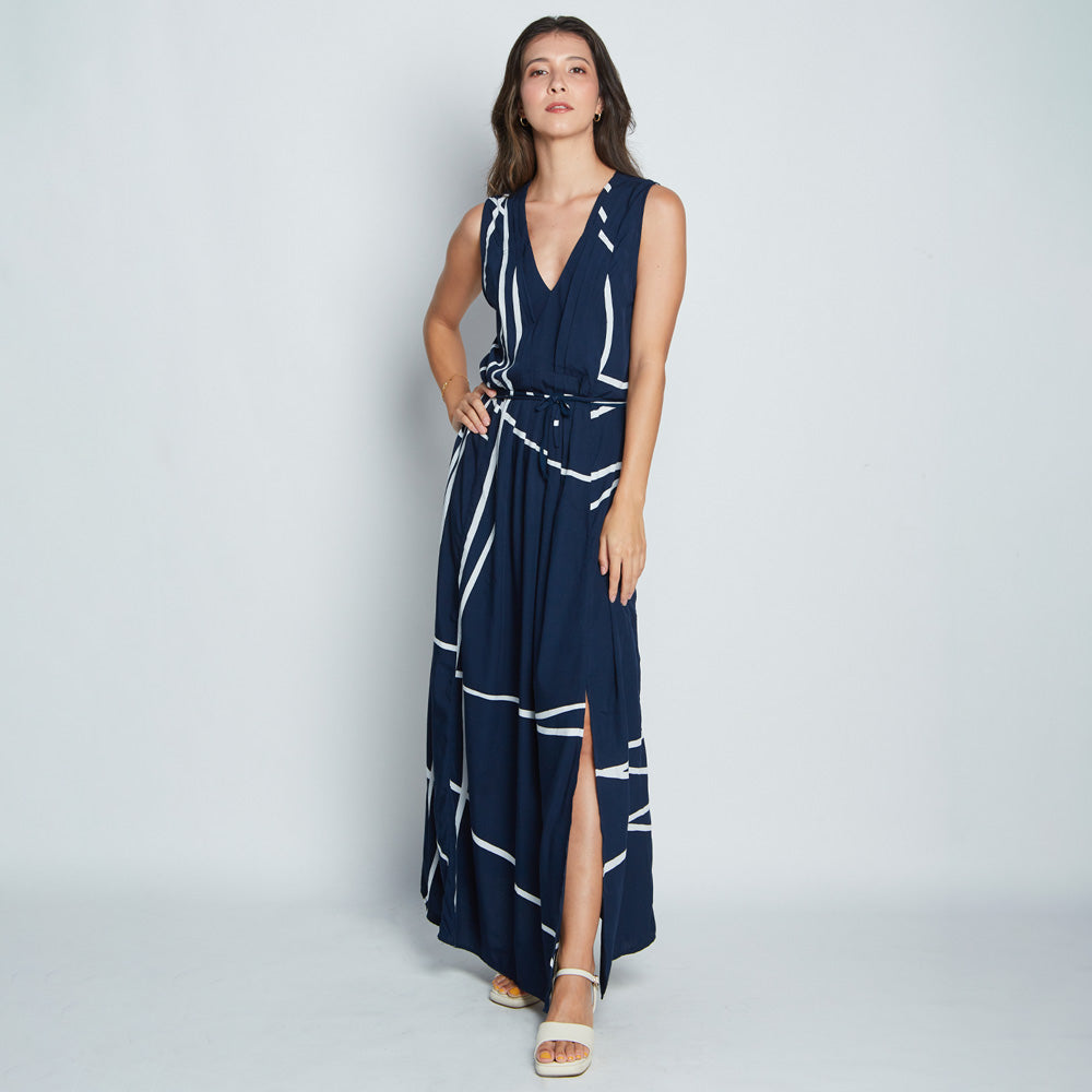 A model is wearing batik maxi dress with medium height slit. The name of pattern is Navy Brush, hand-drawn by local Malaysian artisans