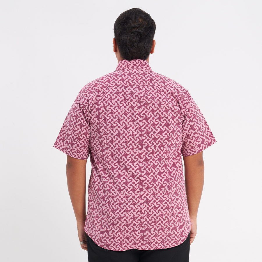 a male model facing away from the camera to capture the details on the back of the batik shirt in the pattern crimson arabesque