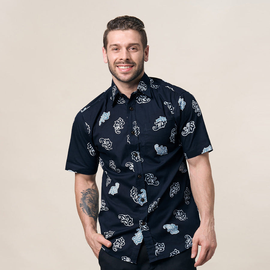 a man standing in front of beige background facing front wearing blue batik shirt in navy cloud pattern