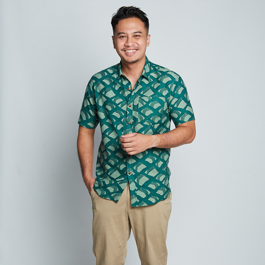 a man posing in front of a neutral background in an authentic batik shirt in the pattern green nasi lemak