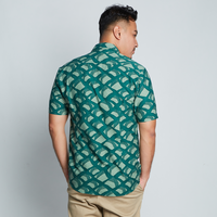 a man posing with his back to the camera in front of a neutral background showcasing the details on the batik shirt in the pattern green nasi lemak