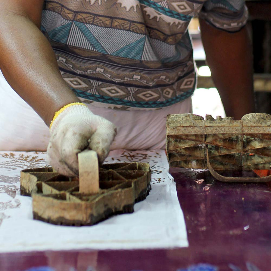 a photo of a batik artisan in the process of blocking in batik motif