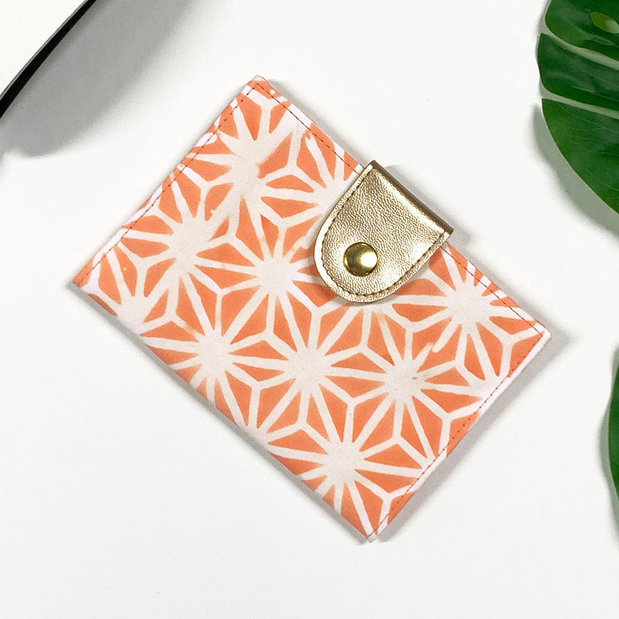 a lifestyle photo of a passport cover in the pattern peach firework made of batik