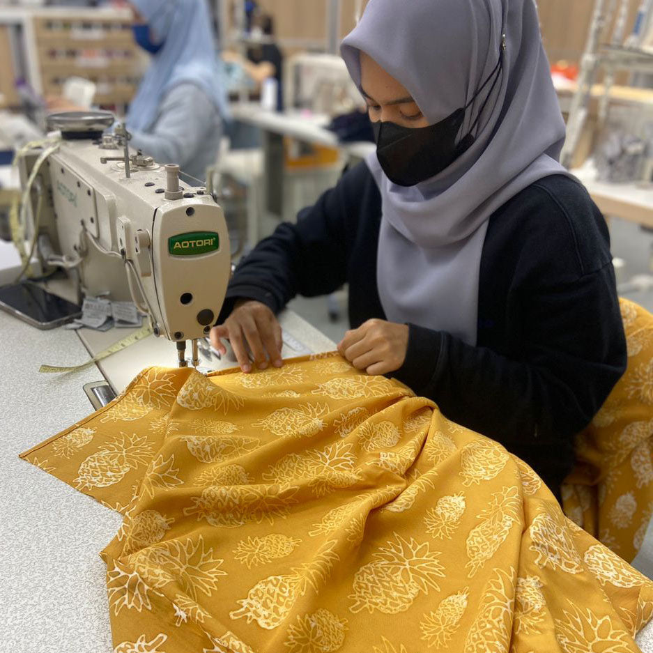 an artisan sewing golden pineapple batik
