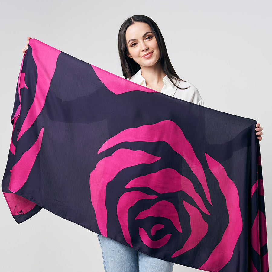 A woman is standing in front of white wall, showing pink color batik long scarf, handcrafted and artisan made locally in Malaysia