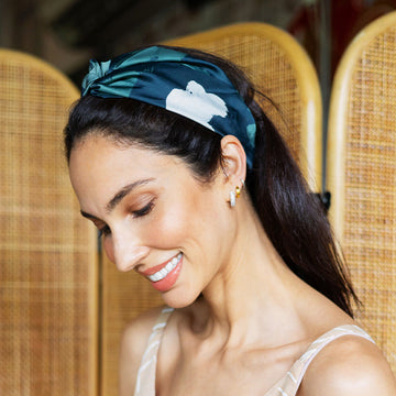 a woman styling batik headband in navy brushed with background of rattan divider