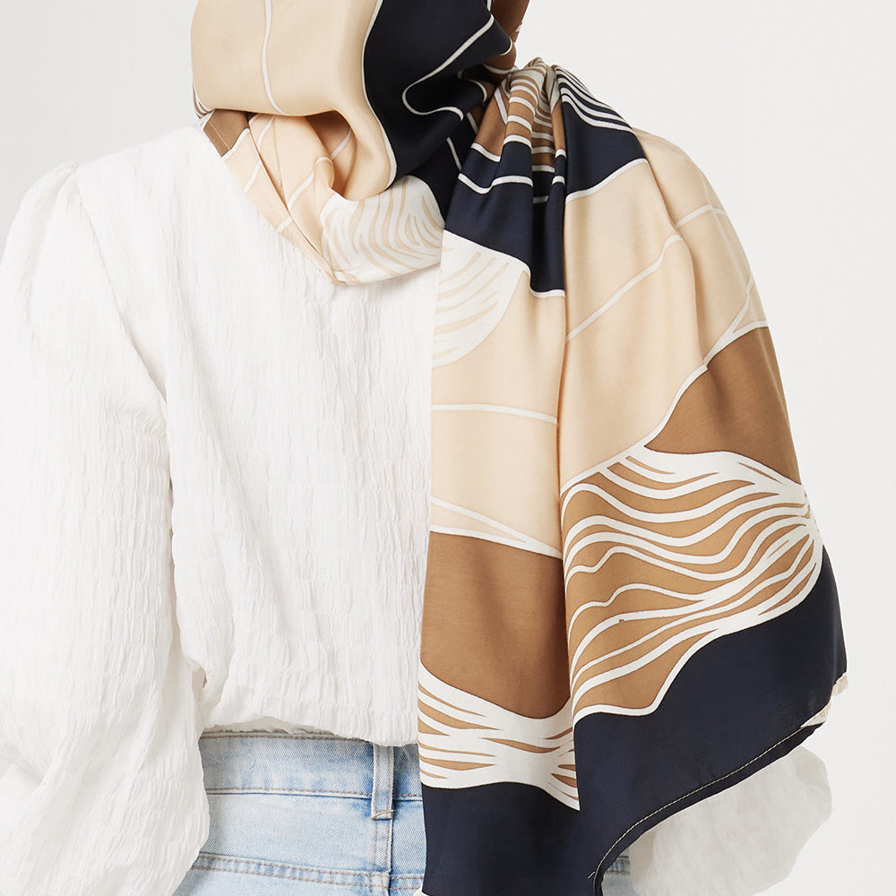a closeup of the back of a woman facing white background styling batik scarf in midnight bukit pattern