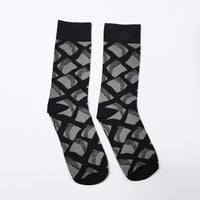 a whitebox photo of full view of a black and grey motif socks. Inspired by batik