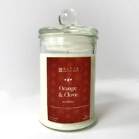 an orange and clove scented candle in front of a white wall