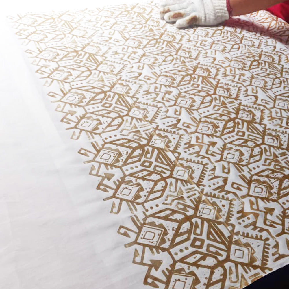 An artisan is batik blocking batik in tikar pattern