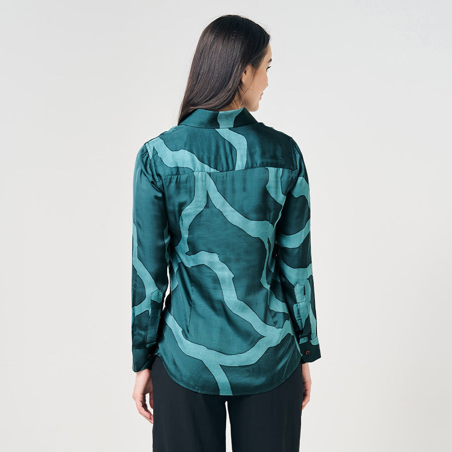 A model gracefully facing the side, emphasizing the exquisite details on the back of the Forest Chain patterned batik shirt against a neutral background