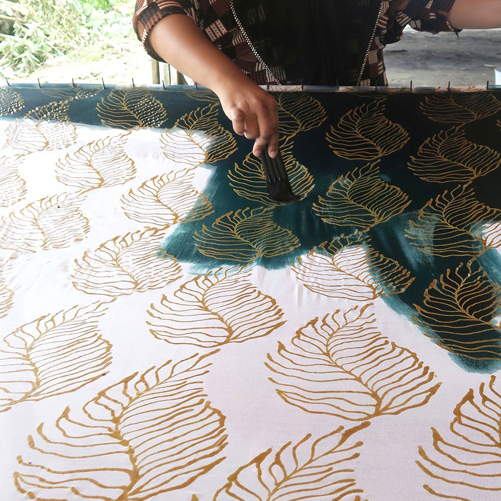 a batik artisan in the process of coloring batik